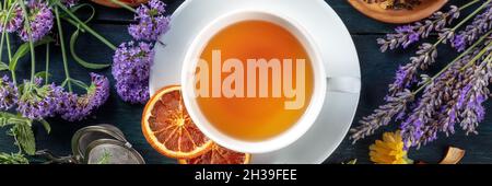 Organic tea panorama with flowers and fruit, shot from the top on a dark rustic wooden background Stock Photo