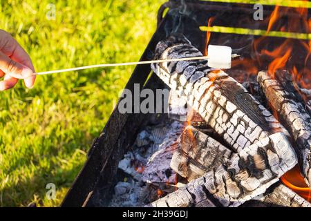 marshmallow on a stick being roasted over a camping fire Stock Photo
