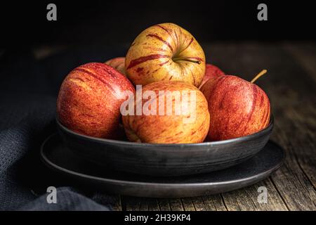 Fresh autumn apples on plate on wooden table. Stock Photo