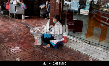 Female Street Food Vendor Sitting on Sidewalk in Chinatown Sampheng Lane Bangkok Thailand Stock Photo