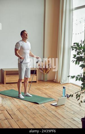 Strong man using resistance bands at home Stock Photo
