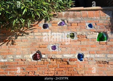 Vintage brick wall with pieces of glass. Orange brick fence from Venice, Italy. Stock Photo