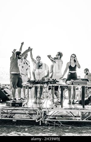 SEVAN, ARMENIA - Sep 03, 2021: A monochrome shot of a group of friends partying on a small concert stage at the beach in Lake Sevan Stock Photo