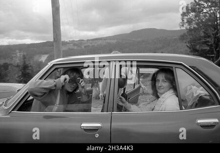 1978 Blue Mountains, Australia: A Year 12 (6th form) teenager (girl/women) school student takes a photo of the photographer using a 110 film pocket instamatic camera while another student watches on. The car in the photo is a Mazda Capella Stock Photo