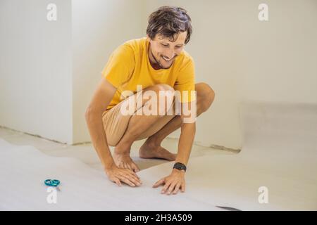 man and a roll of insulating cloth to install a laminate wooden floor Stock Photo