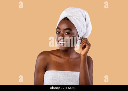 Portrait of smiling black woman using serum Stock Photo