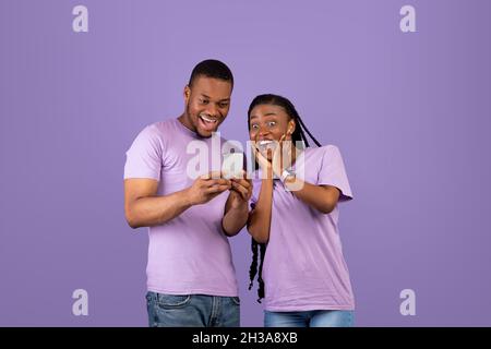 Portrait of surprised black couple using smartphone Stock Photo
