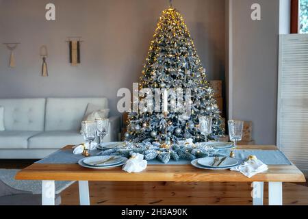 Beautiful served table with turquoise tablecloth and napkins, gold cutlery, crystal champagne glasses. Table setting family dinner. Blurred Christmas Stock Photo