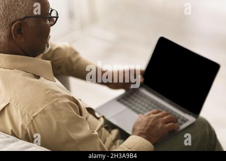 Unrecognizable Senior African Man Using Laptop With Blank Screen Indoors Stock Photo