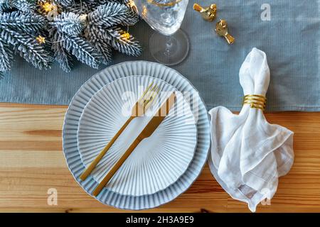 Beautiful Christmas table setting on wooden table. Festive place setting for christmas dinner in golden and blue color. Top view Stock Photo