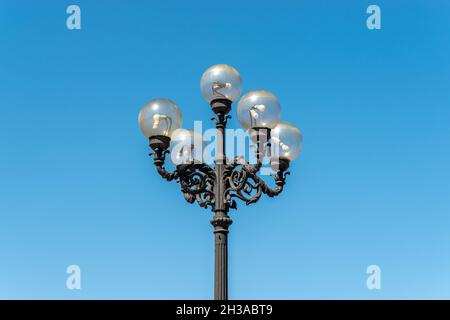 Old lamppost on street with blue sky background. Stock Photo