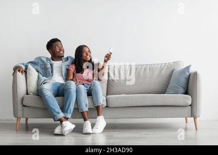 Young black woman switching on air conditioning at her home Stock Photo