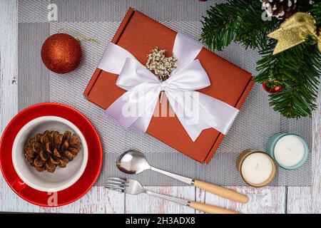 Christmas dinner table decorations with a red gift box and scented candles Stock Photo