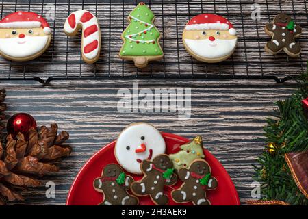 Sugar coated biscuits and Christmas theme cookies on a baking rack and a red ceramic plate with Christmas ornaments. Stock Photo