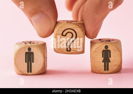 Man holding a wooden cube with a question mark near two other cubes, the concept of the relationship between a man and a woman and the complexity of g Stock Photo
