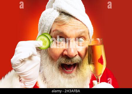 Close-up funny senior man wearing white towl and costume of Santa Claus congrats everybody with New Year 2022 Stock Photo