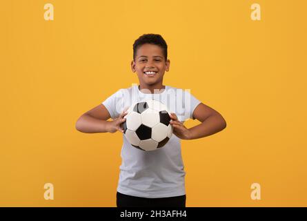 Cheerful black school boy holding soccer ball Stock Photo