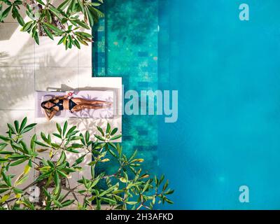 Top view drone Asian woman laying on the poolside in Lombok, Indonesia Stock Photo