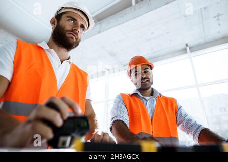 Portrait of two young construction engineers wearing hardhats on construction site Stock Photo