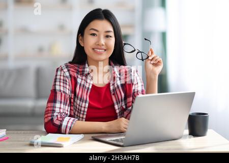 Young Beautiful Asian Woman Posing At Desk With Laptop In Home Office Stock Photo