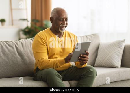 Mature African American Man Using Digital Tablet Sitting At Home Stock Photo