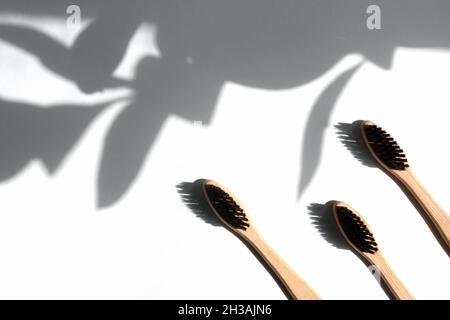 Bamboo toothbrushes isolated on white concrete background with plant shadows. The concept of personal hygiene, dentistry, zero waste, environmental fr Stock Photo
