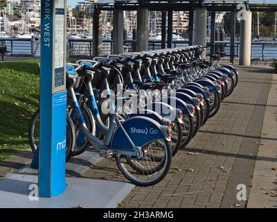 View bicycles in a row at Mobi bike share station in West David Lam Park, False Creek, operated by Vancouver Bike Share Inc. with Shaw Go advert. Stock Photo