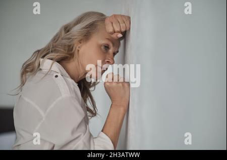 Dejected mature blonde woman suffering from loneliness Stock Photo