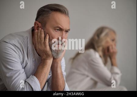 Cheerless silent man sitting apart from his wife Stock Photo