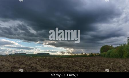 Rain and storm clouds over plowed agricultural field, Eifel, Germany Stock Photo