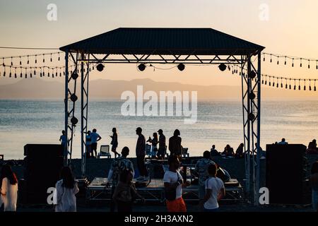 SEVAN, ARMENIA - Sep 03, 2021: A group of young people enjoying the beach party on the shore of Lake Sevan at sunset Stock Photo