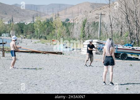 SEVAN, ARMENIA - Sep 03, 2021: A group of young people playing volleyball on the beach at Lake Sevan, Armenia Stock Photo