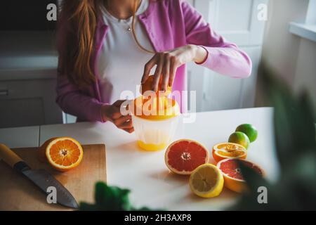 Woman squeezing oranges to make a natural citrus juice. Morning routine. Stock Photo