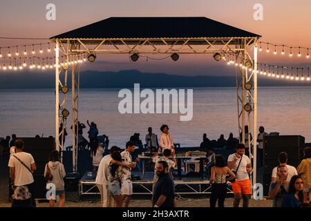 SEVAN, ARMENIA - Sep 03, 2021: A group of young people enjoying the beach party on the shore of Lake Sevan at sunset Stock Photo
