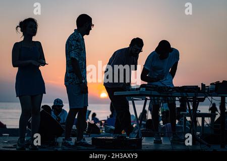 SEVAN, ARMENIA - Sep 03, 2021: A group of young people enjoying the beach party on the shore of Lake Sevan at sunset Stock Photo
