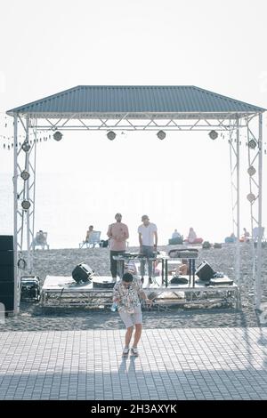 SEVAN, ARMENIA - Sep 03, 2021: A group of young people enjoying the beach party on the shore of Lake Sevan at sunset Stock Photo