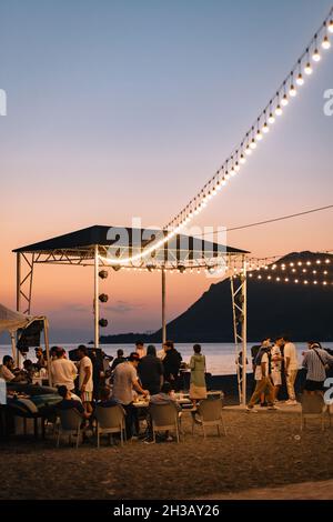 SEVAN, ARMENIA - Sep 03, 2021: A group of young people enjoying the beach party on the shore of Lake Sevan at sunset Stock Photo