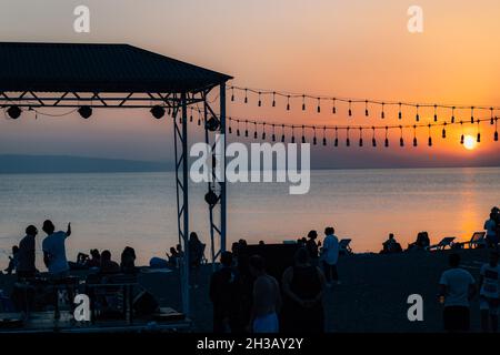 SEVAN, ARMENIA - Sep 03, 2021: A group of young people enjoying the beach party on the shore of Lake Sevan at sunset Stock Photo