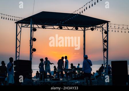 SEVAN, ARMENIA - Sep 03, 2021: A group of young people enjoying the beach party on the shore of Lake Sevan at sunset Stock Photo