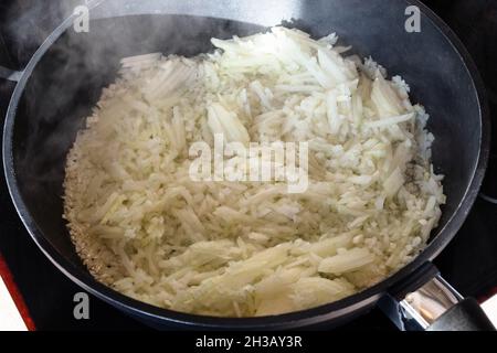 finely chopped onions sauteing in deep frying pan at home kitchen Stock Photo