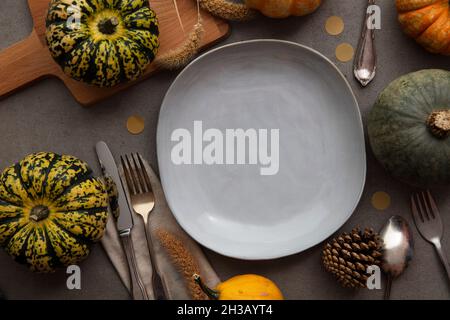 Overhead autumn thanksgiving dinner place setting with pumpkins cutlery and an empty plate Stock Photo