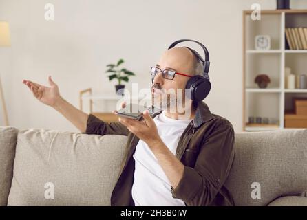 Man in headphones talking on speakerphone, recording message, or using voice assistant Stock Photo