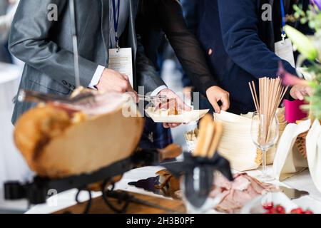 Businesspeople at banquet lunch break at business conference meeting. Assortment of food and drinks. Stock Photo