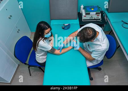 Physician working on examining a girl's injured hand Stock Photo