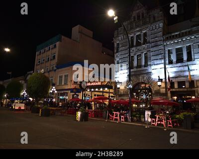 Beautiful night view of busy Government St in historic Victoria downtown, Vancouver Island with the entrance to Bastion Square. Stock Photo