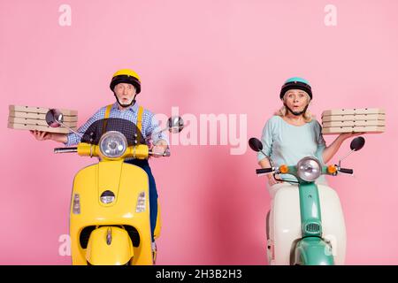 Photo of excited hurry courier mature couple excited sale reaction ride scooter deliver pizza isolated on pink background Stock Photo
