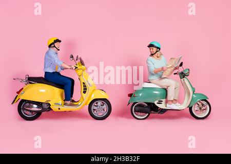 Full size profile side photo of smiling mature couple white grey hair ride moped hold map checking route isolated on pink color background Stock Photo