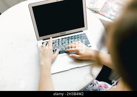 Blurry girl working with laptop, focus on computer. Stock Photo