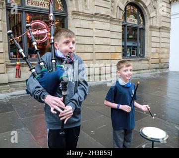 Glasgow, UK. 27th Oct, 2021. CALUM PEARSON aged 13 (piper) and his brother DANIEL PEARSON, aged 9, (drummer) from Aberdeen were visiting Glasgow with their parents (present) and while on holiday, were busking in Buchanan Street, in the city centre, to augment their holiday pocket money. Both Calum and Daniel are members of Buckburn and District Pipe Band from Aberdeen. Calum has been playing the bagpipes for 4 years and Daniel has been drumming for 2 years. Credit: Findlay/Alamy Live News Stock Photo