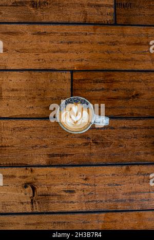 Lavender latte on wood floor with rosetta latte art and lavender dried flower garnish.